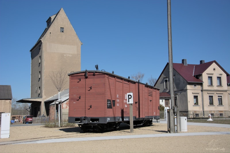 Eisenbahngeschichte: Güterwagen der Döllnitztalbahn und alter Speicher in Mügeln